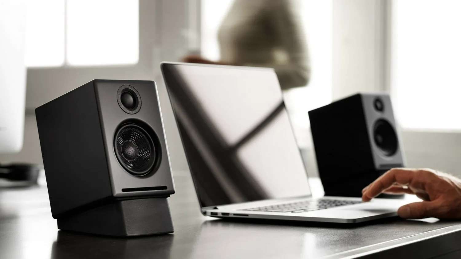 Pair of Audioengine A2+ Gen 3 speakers on a desk beside an open laptop