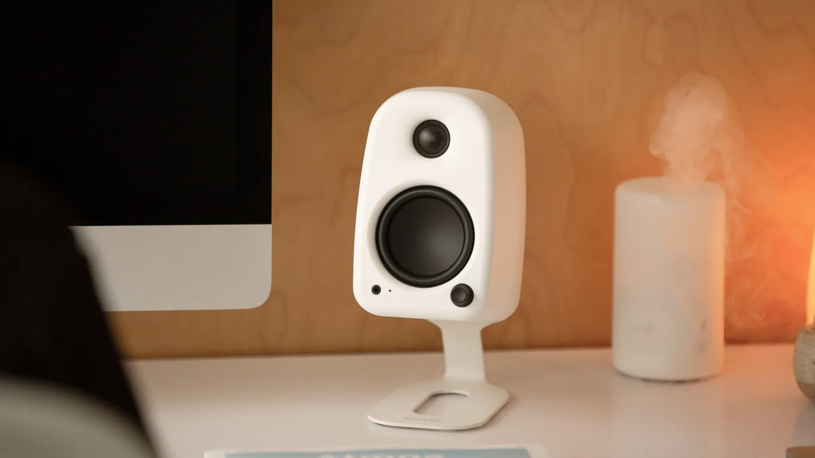 Kanto Uki speaker in white on a desk next to a monitor