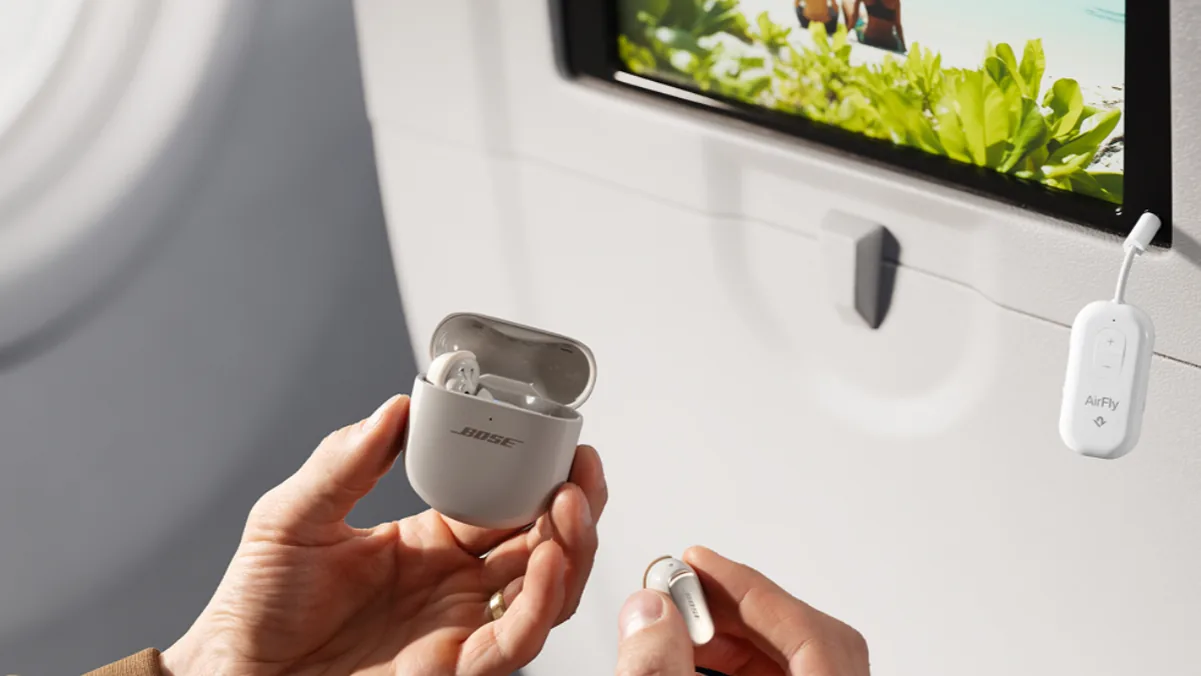 AirFly Pro 2 plugged into an airplane seatback headphone jack next to the screen