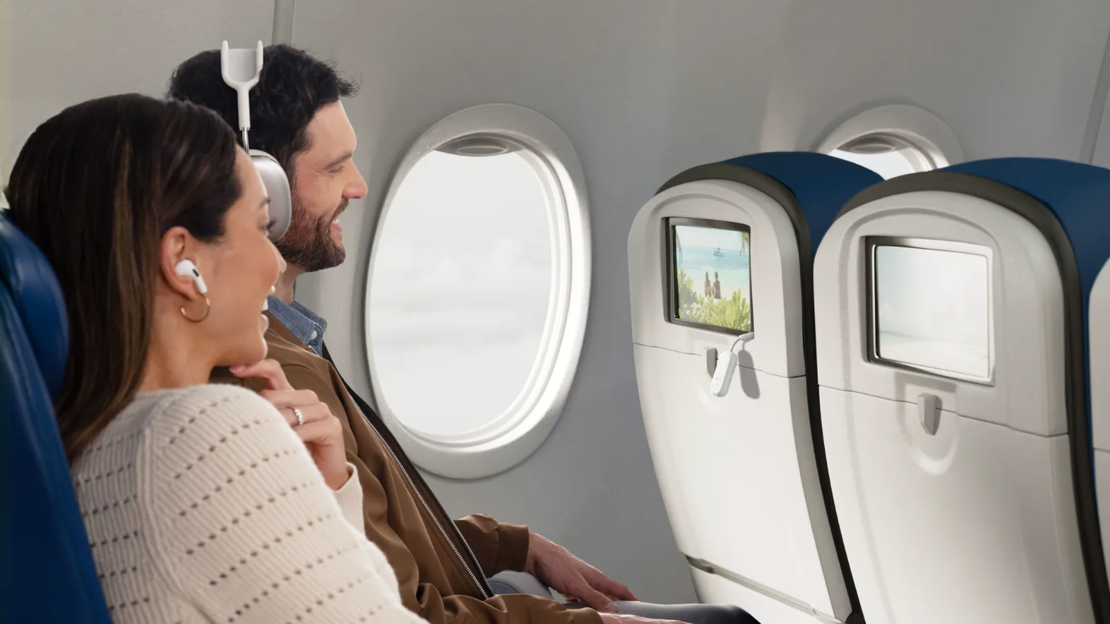 Two passengers on a plane watching the same seatback screen with wireless headphones