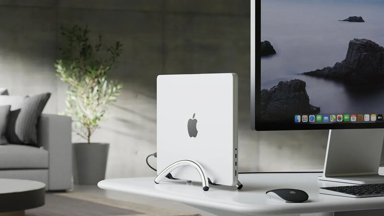 MacBook Pro standing upright in a chrome BookArc Flex beside an external display, with open space around the laptop